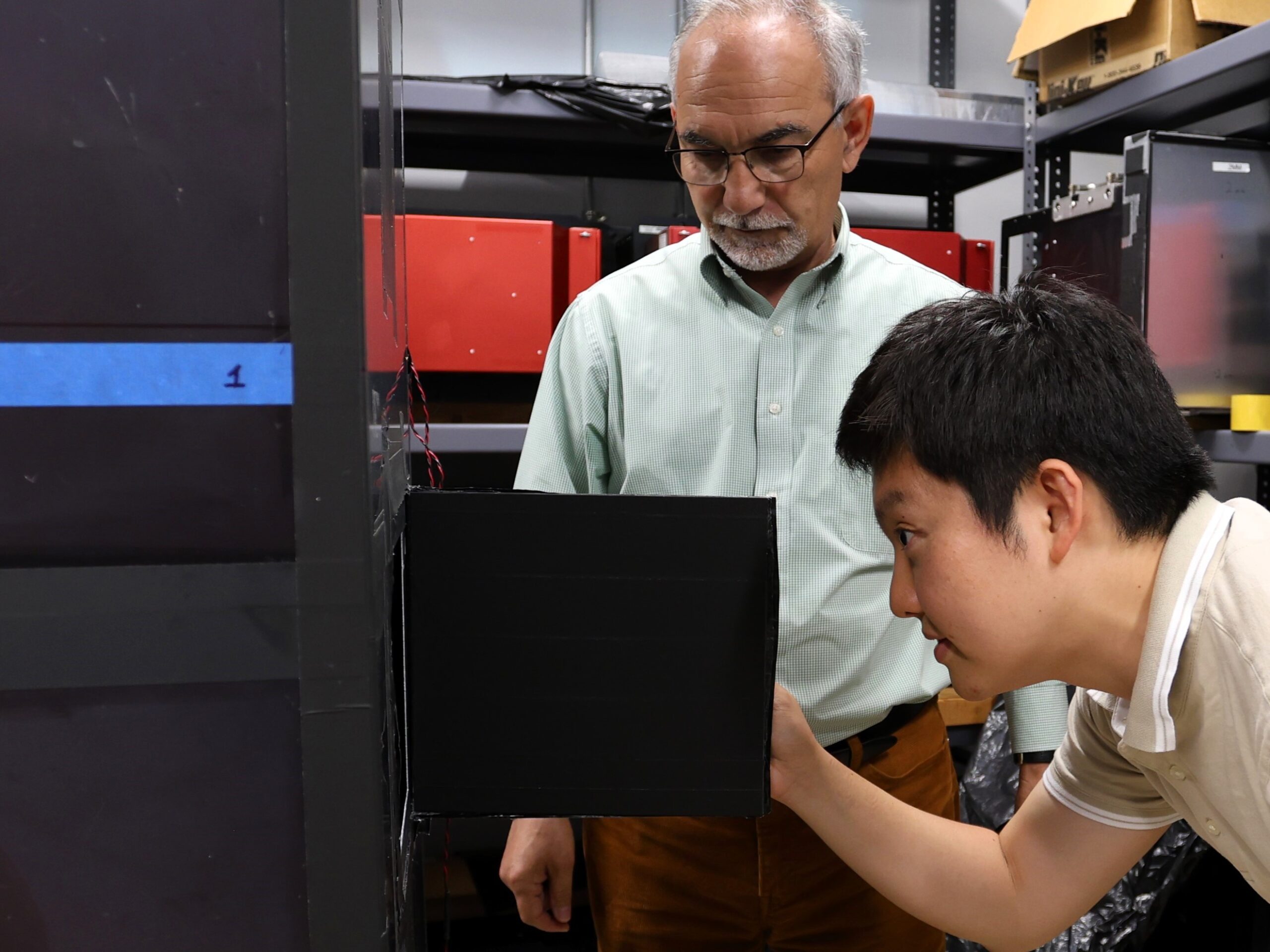 Lead muon detector developer Polad Shikhaliev looks on as JungHyun Bae, a Wigner Distinguished Staff Fellow at ORNL, looks inside a muon detector he envisioned during his doctoral studies.
