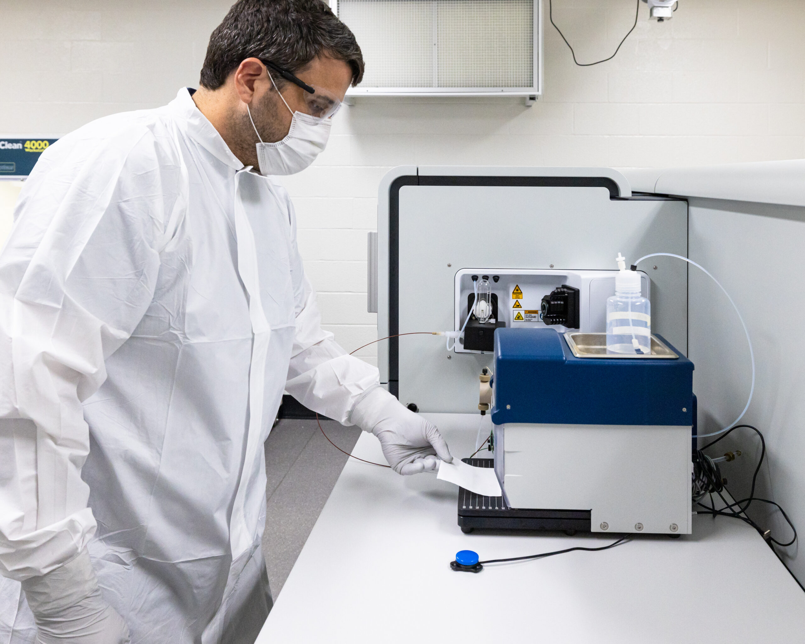 Benjamin Manard standing in front of mass spectrometer on counter top.