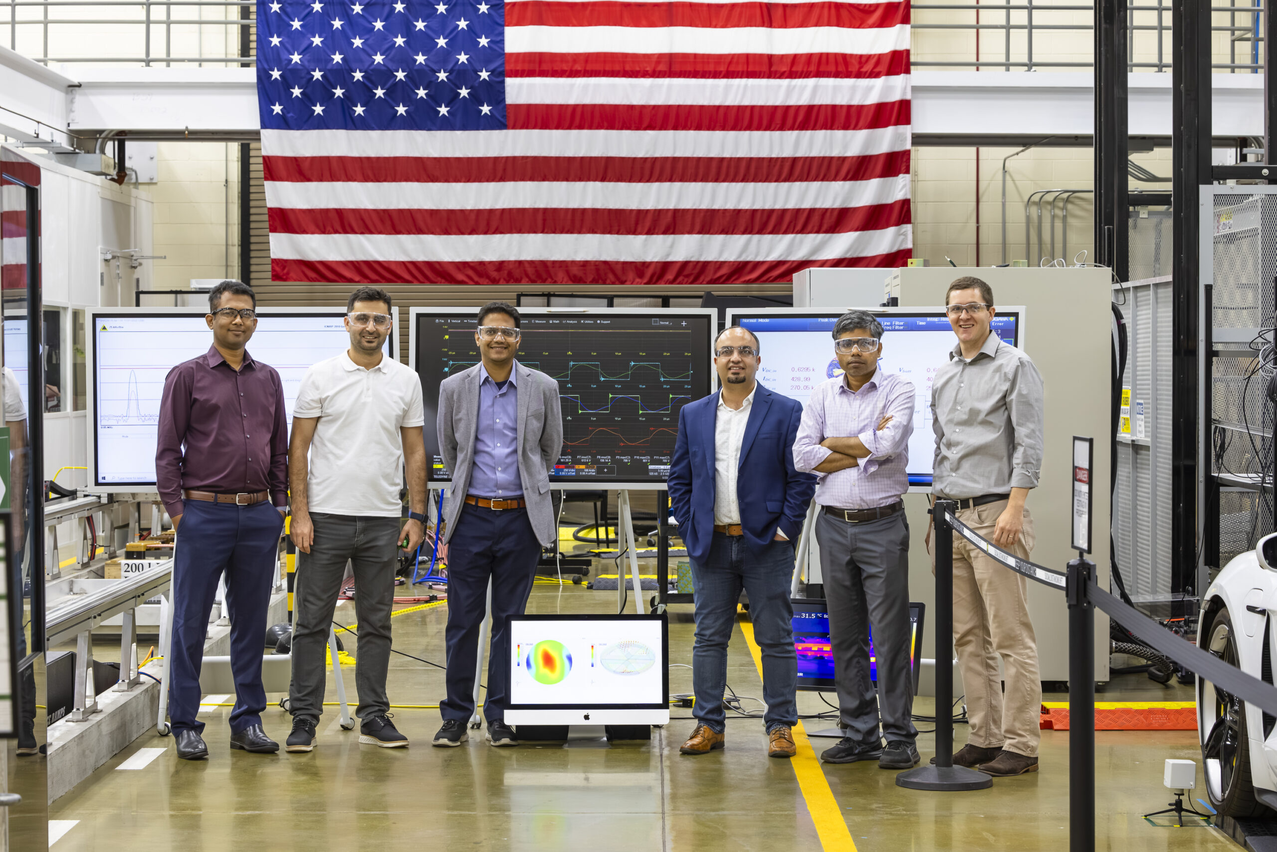 Six men are standing next to each other in front of an American flag