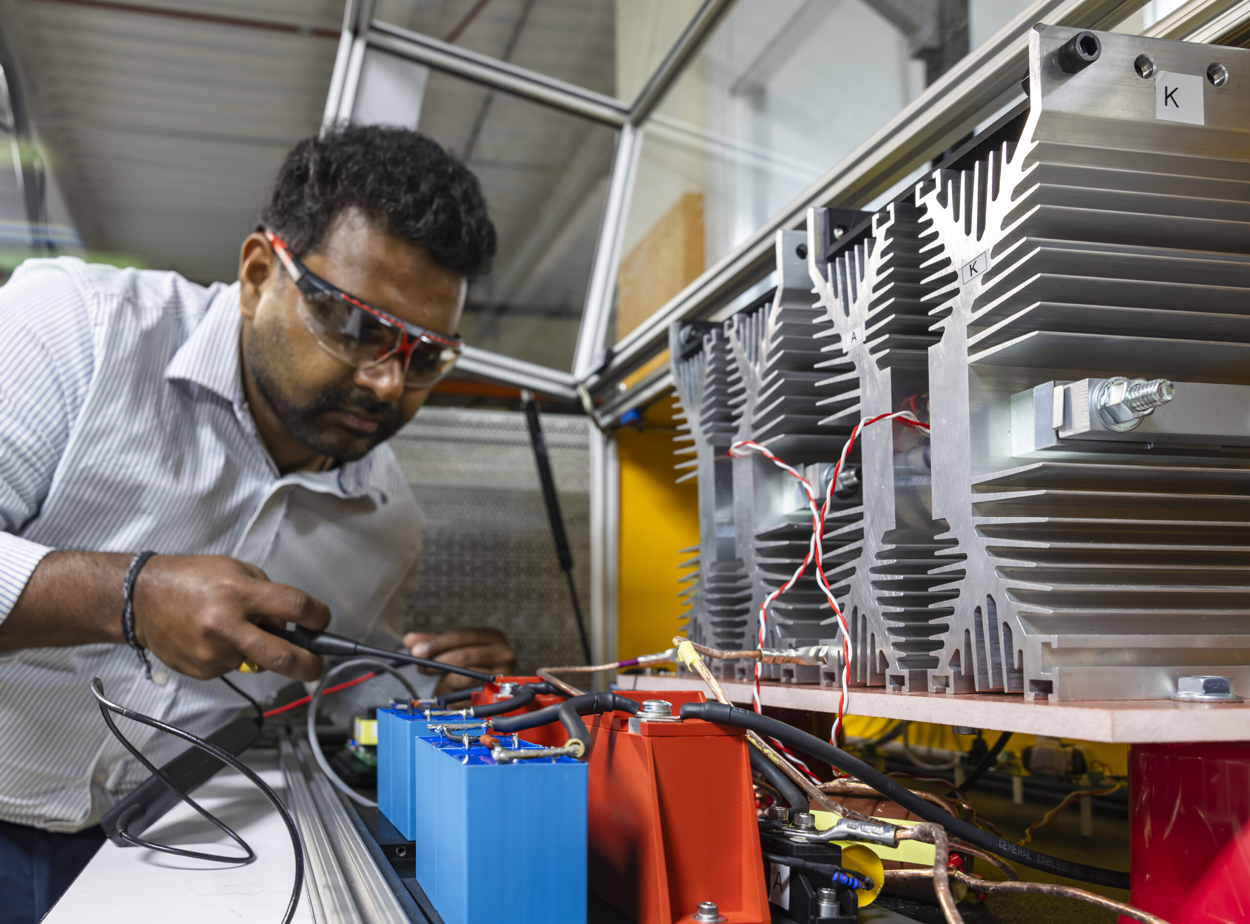 Engineer testing battery components with probes in a lab setting.