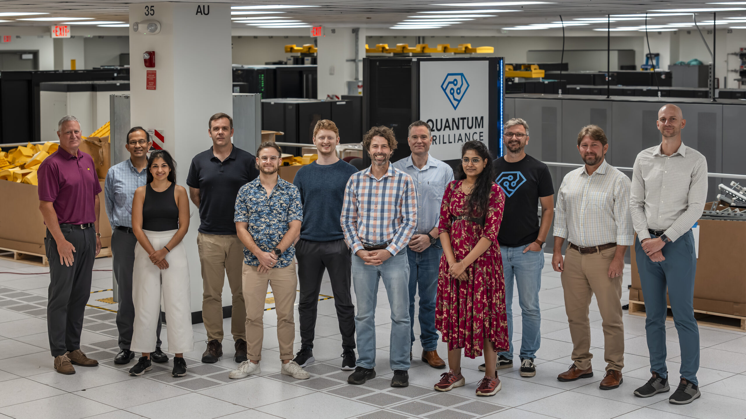 Group photo of team standing in front of the Quantum Brilliance logo
