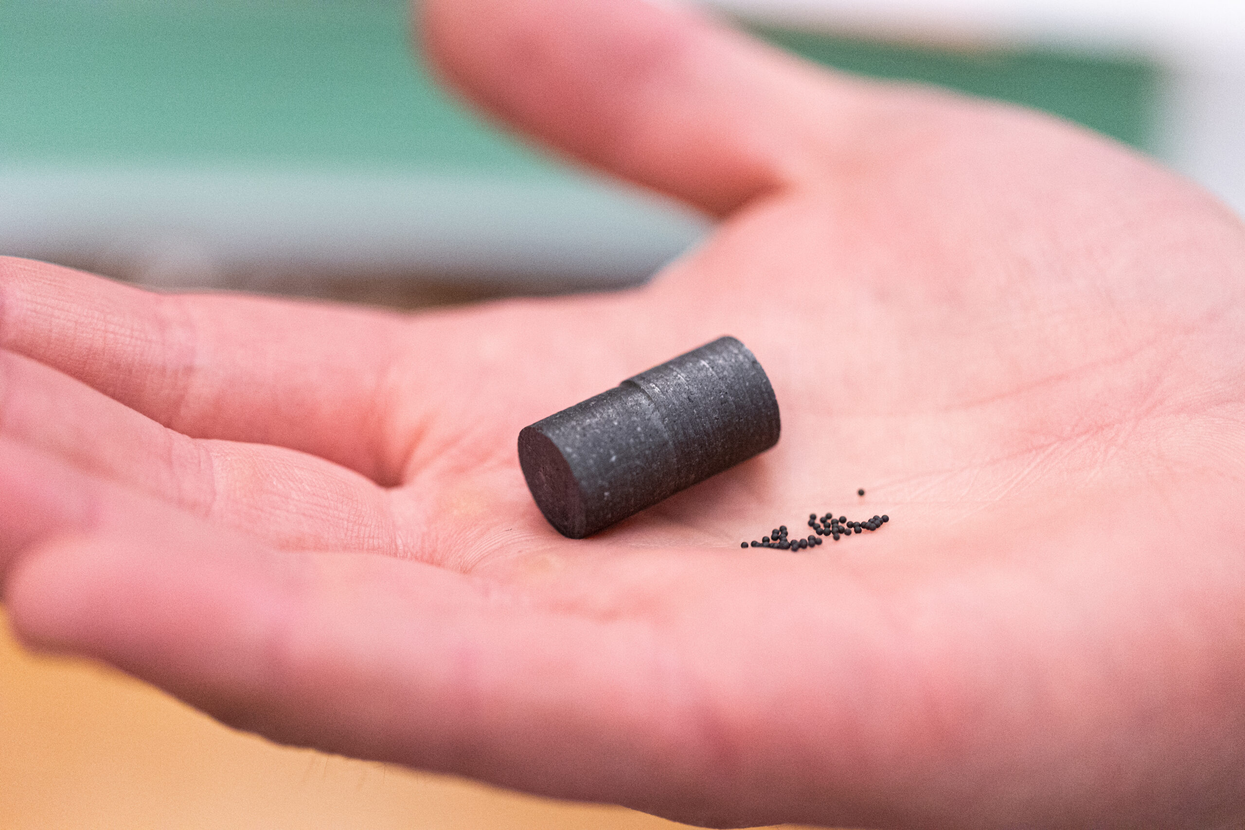 A small tube-like black object on a person's palm of their hand.