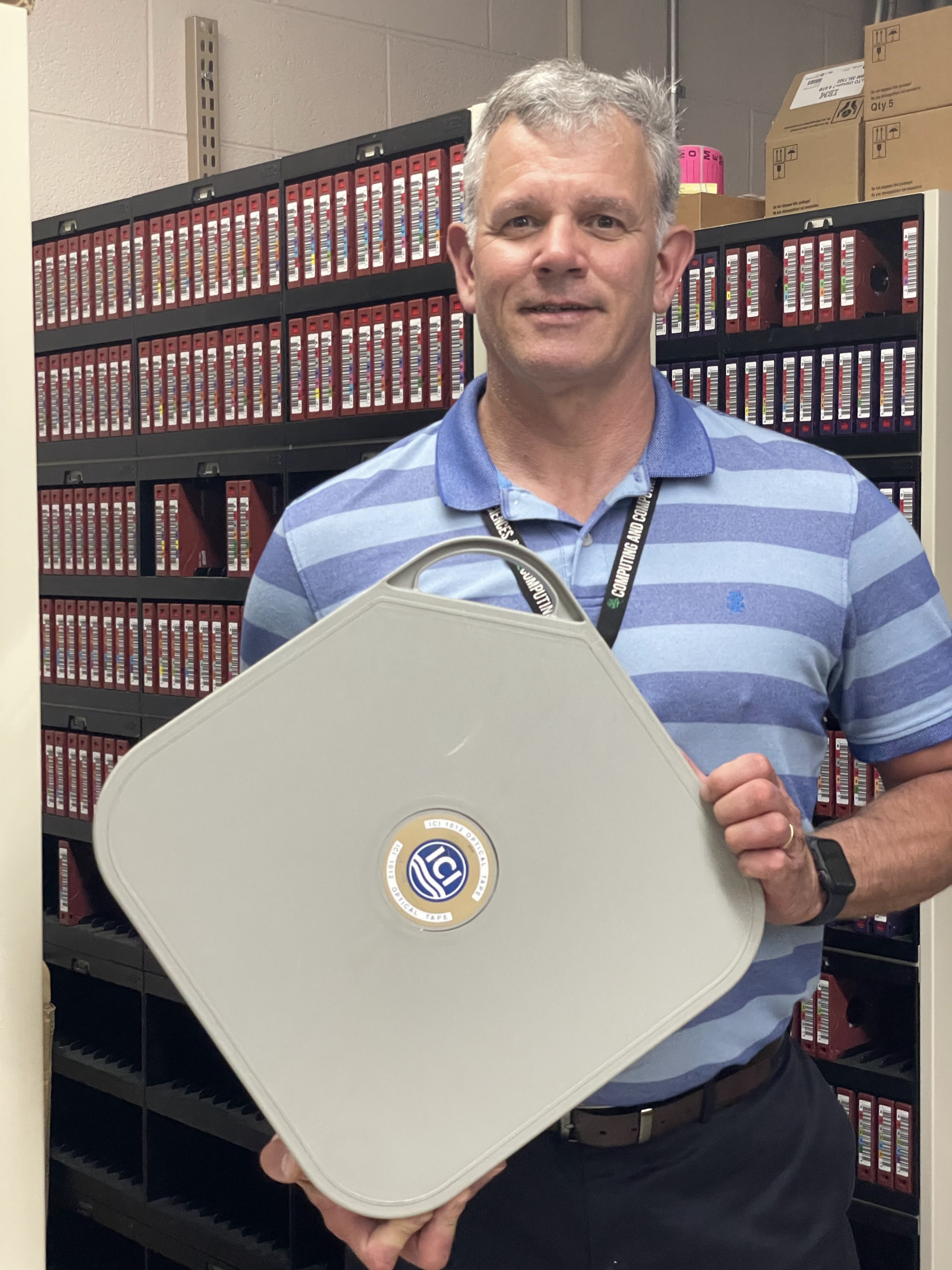 Rob Records, ARM Data Center operations lead at ORNL, holds ARM’s first optical tape container, deemed full around October 16, 1996. The tape holds a terabyte of data. Today, ARM pulls in that much data about every eight hours. Credit: Giri Prakash/ORNL,