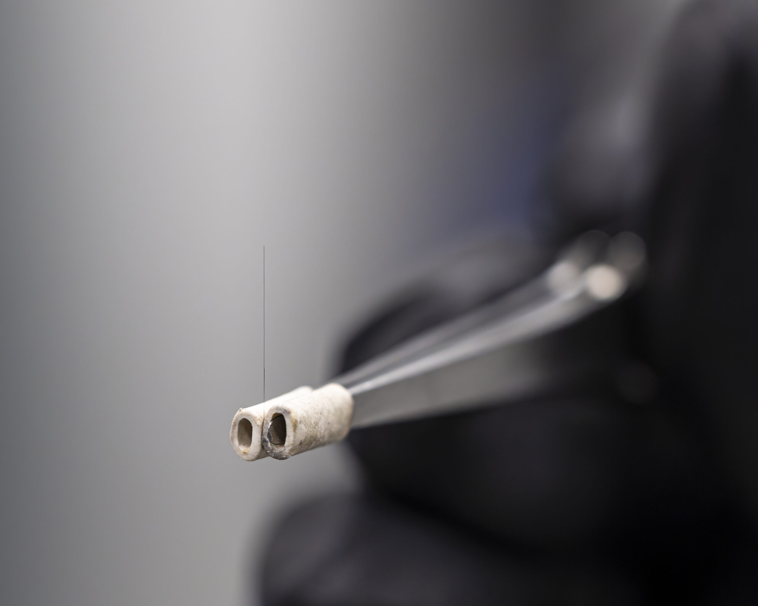 A close-up photo of carbon fiber that is being held on a pair of tweezers.