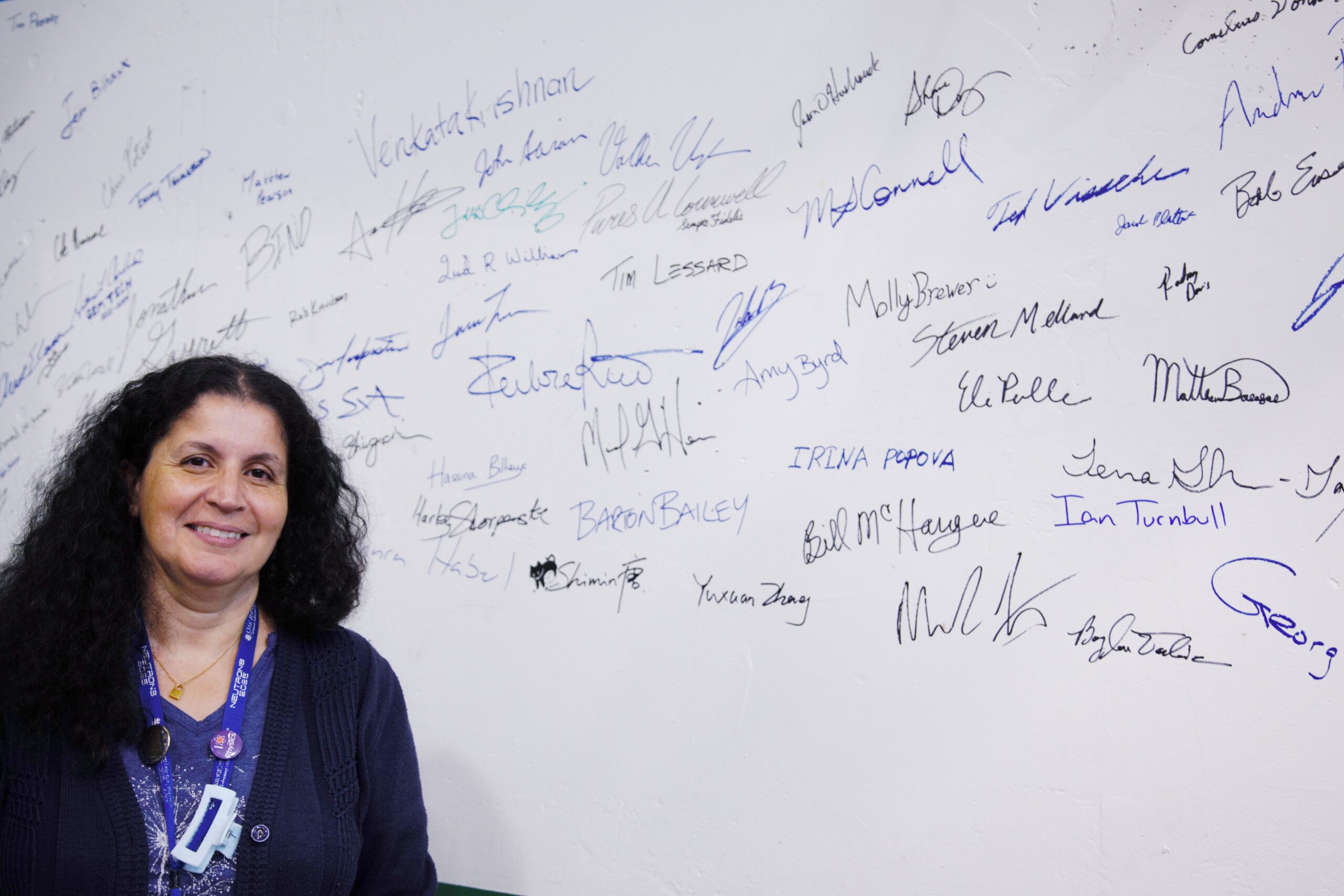 ORNL’s Hassina Bilheux stands before names of staff who have worked on the Spallation Neutron Source’s latest addition, the Versatile Neutron Imaging Instrument, or VENUS.