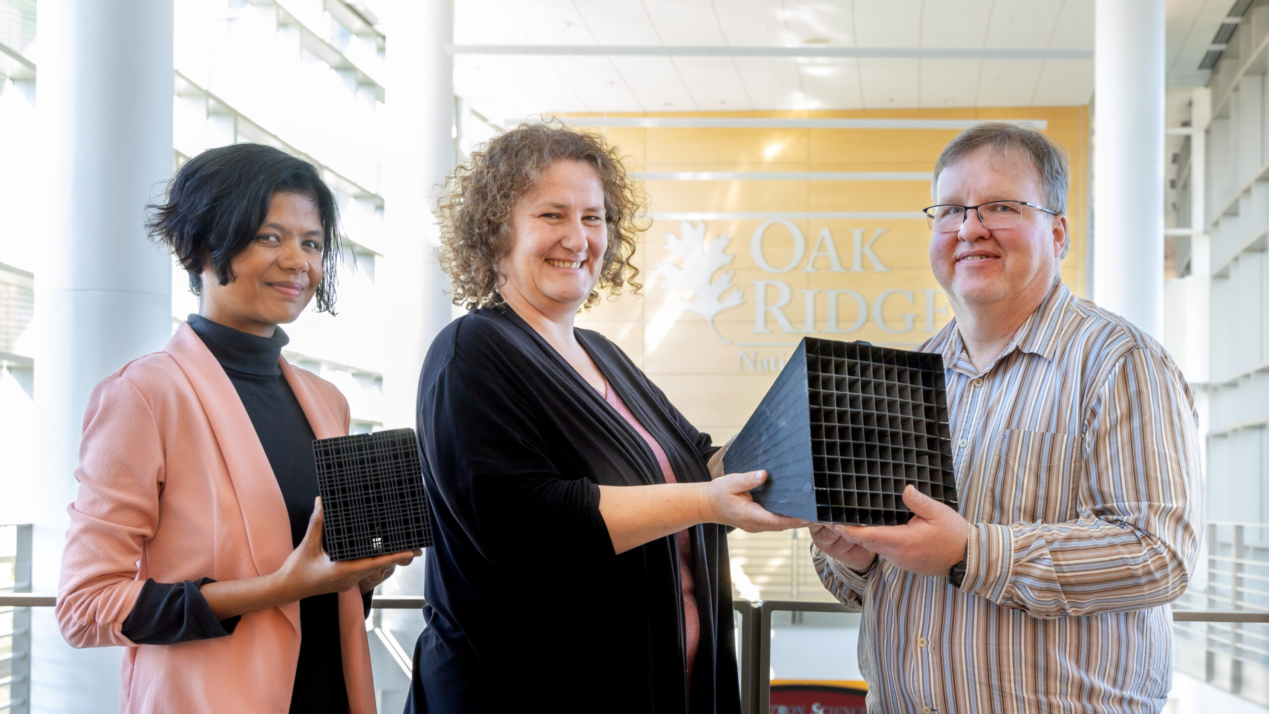 The team of three people who created the 3d printed callimator posing with it