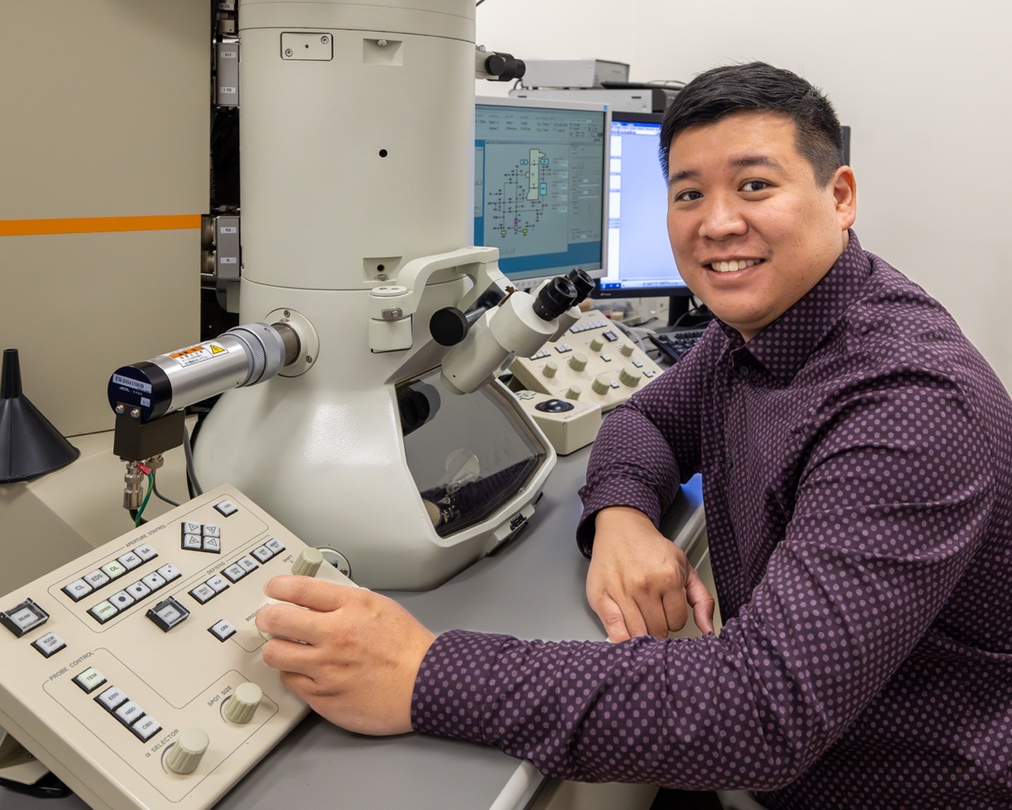 ORNL researcher is sitting at a transmission electron microscopy board in a lab at ORNL