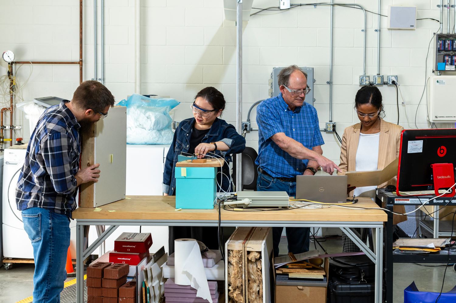 Researchers are looking at computers, working with a bright blue box in the middle of the table