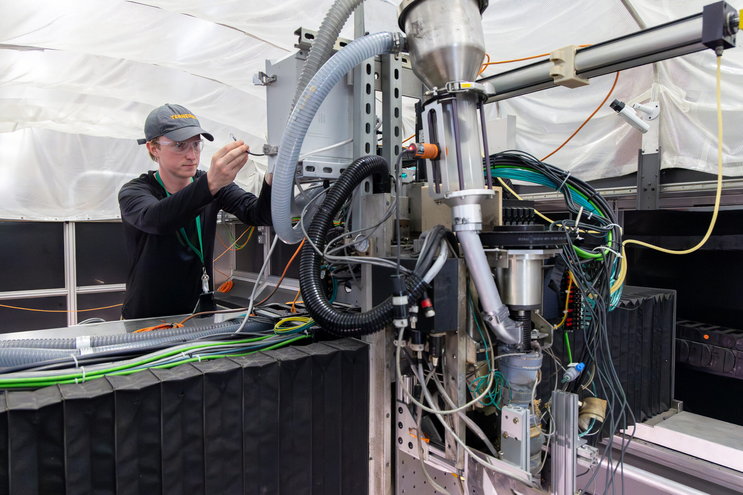 Researcher works on a sensor-equipped large-scale 3D printing system in a manufacturing lab.