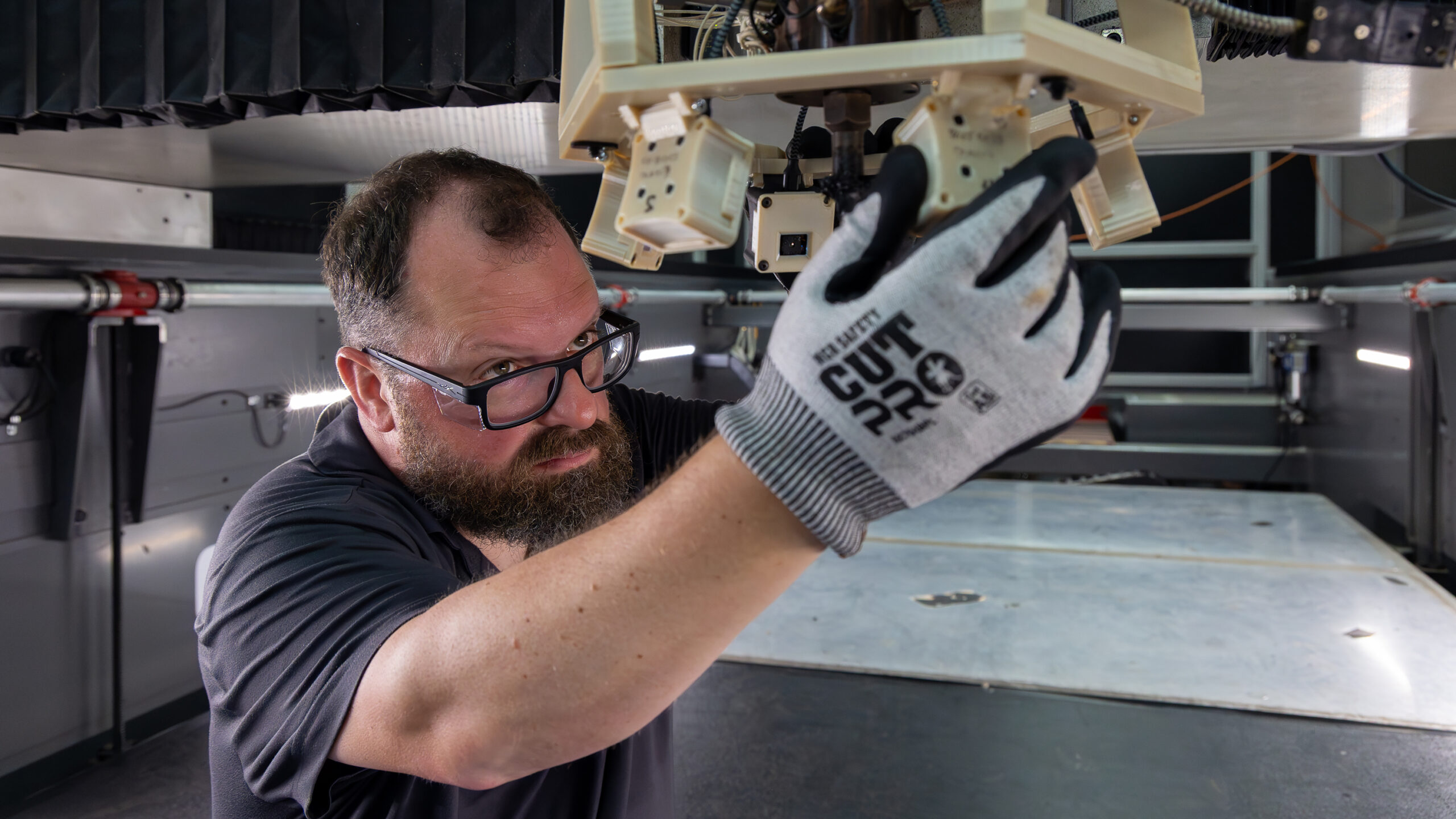 Researcher adjusts sensors on a large-scale 3D printer used for automated monitoring and error correction.