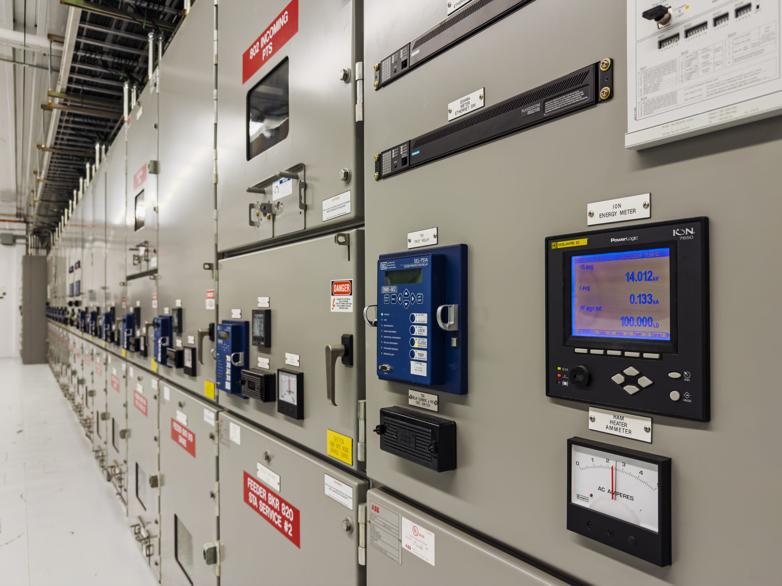 A row of electrical switchgear cabinets with digital meters and control equipment in a power distribution facility.