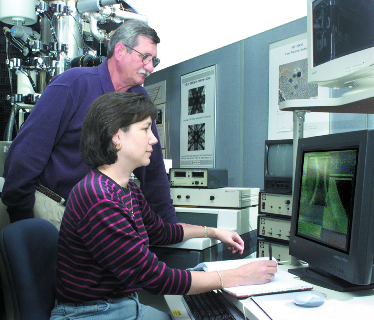 Two engineers working on a complex industrial machine with gauges and wiring.