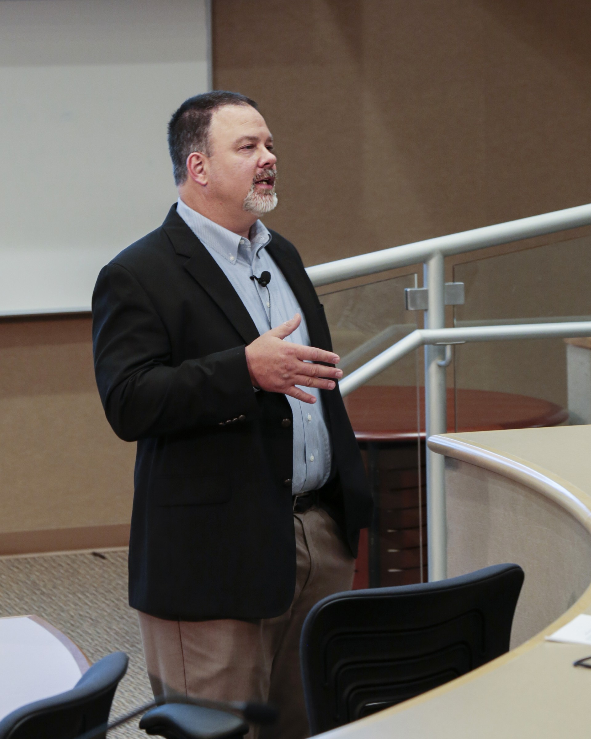 Man giving a presentation in a lecture room, gesturing while speaking