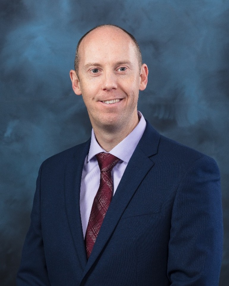 Photo portrait of David Culle in a navy suit with a grey and navy background