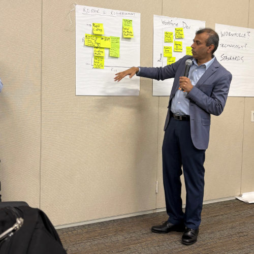 Man at wall pointing at large papers with sticky notes
