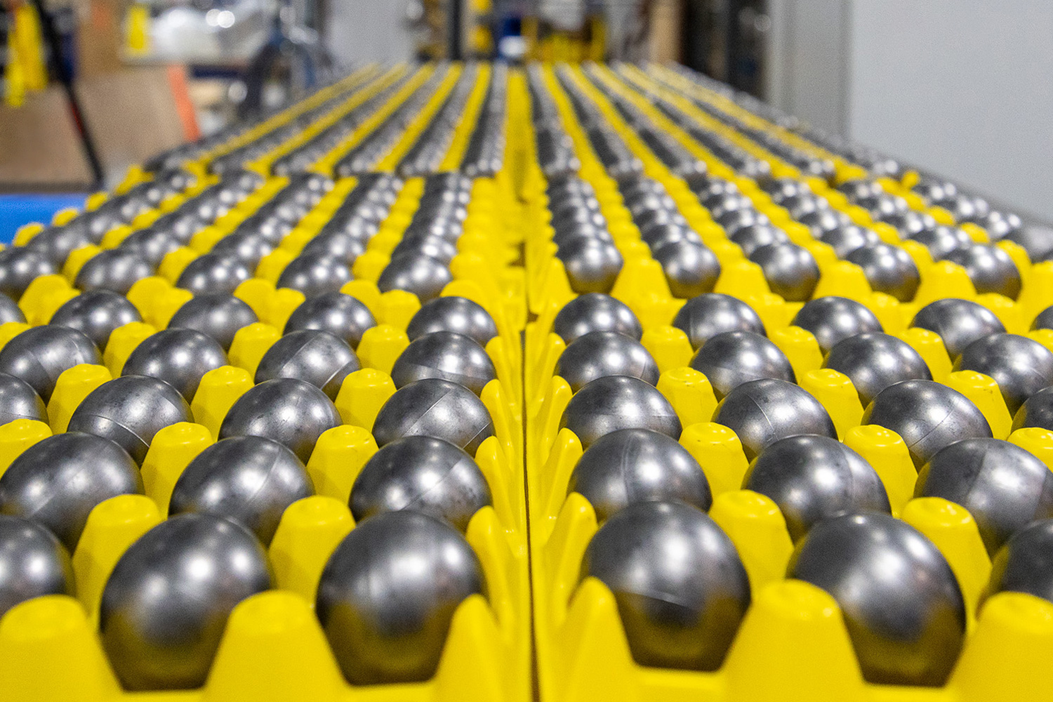 Rows of metallic spherical pellets arranged in bright yellow trays inside a laboratory.