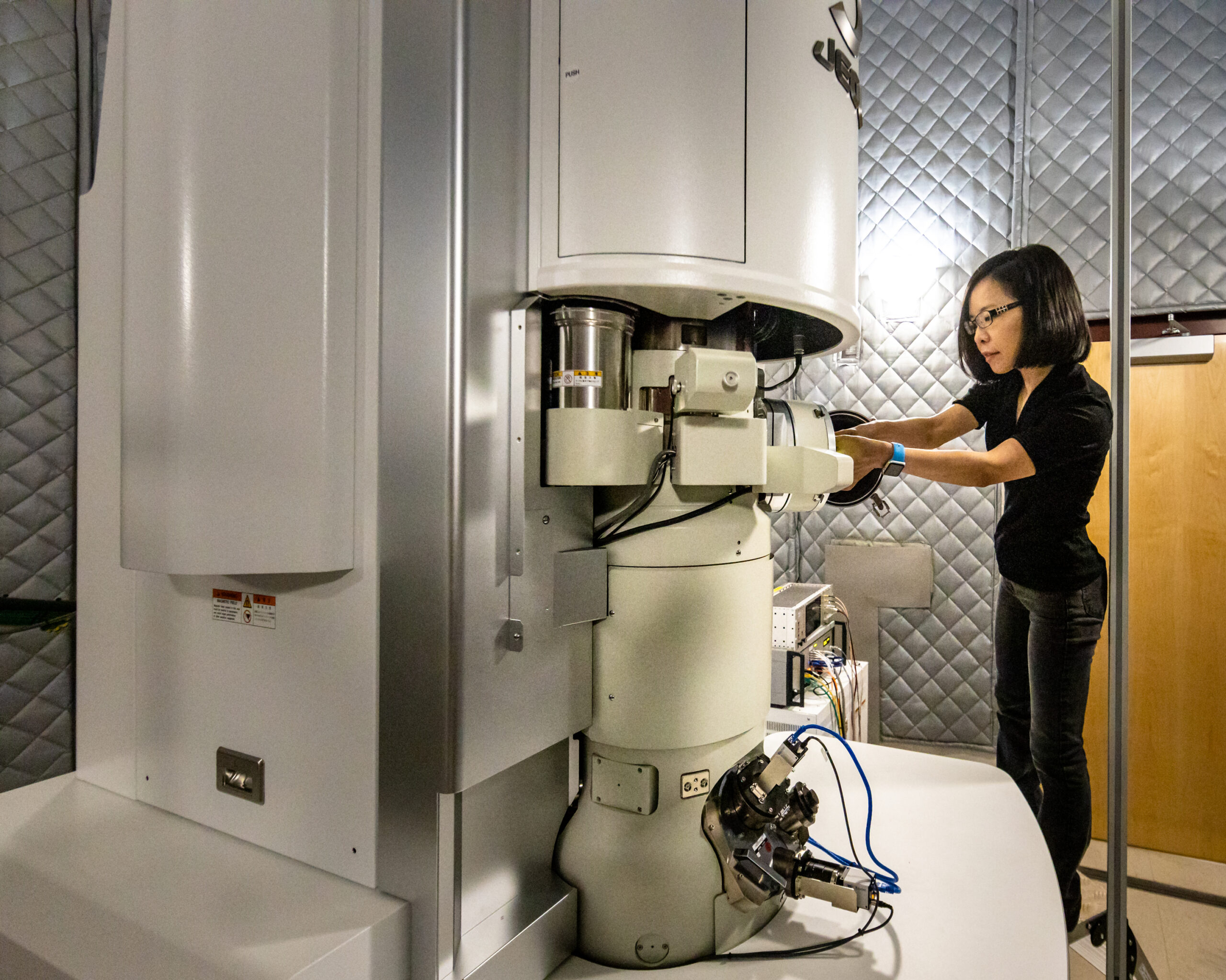 A person works on a complicated piece of machinery in a gray room.