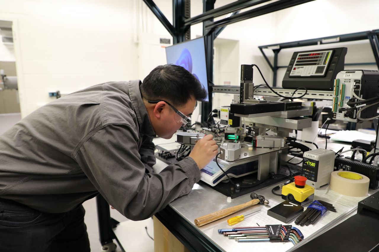 Researcher carefully working with precision lab equipment in an advanced engineering lab