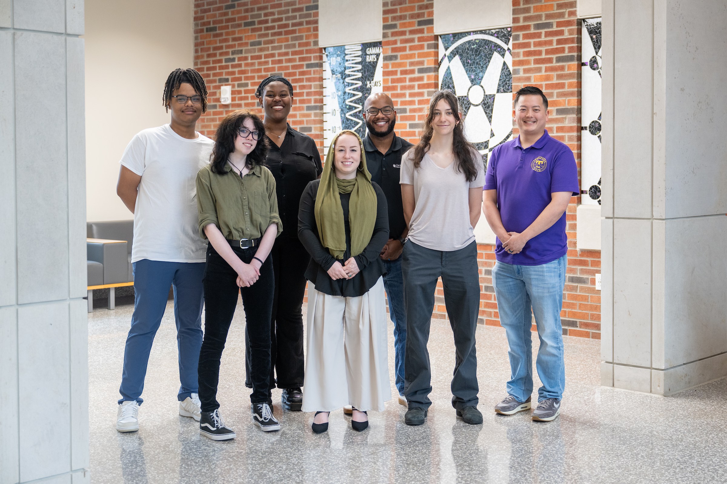 Group of students and mentors posing together inside a science and engineering building.