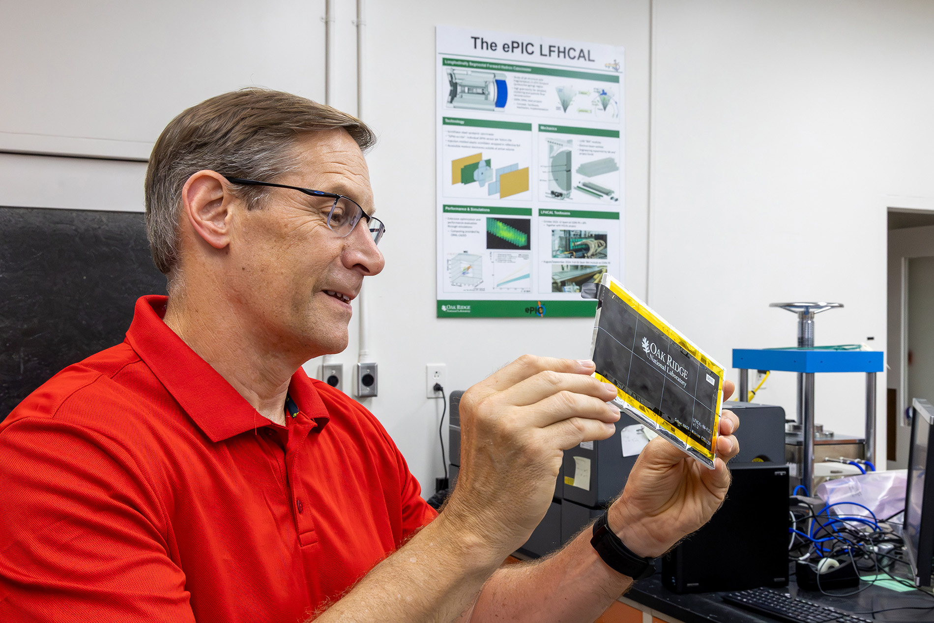 A researcher examines a prototype particle detector component in an Oak Ridge National Laboratory lab.