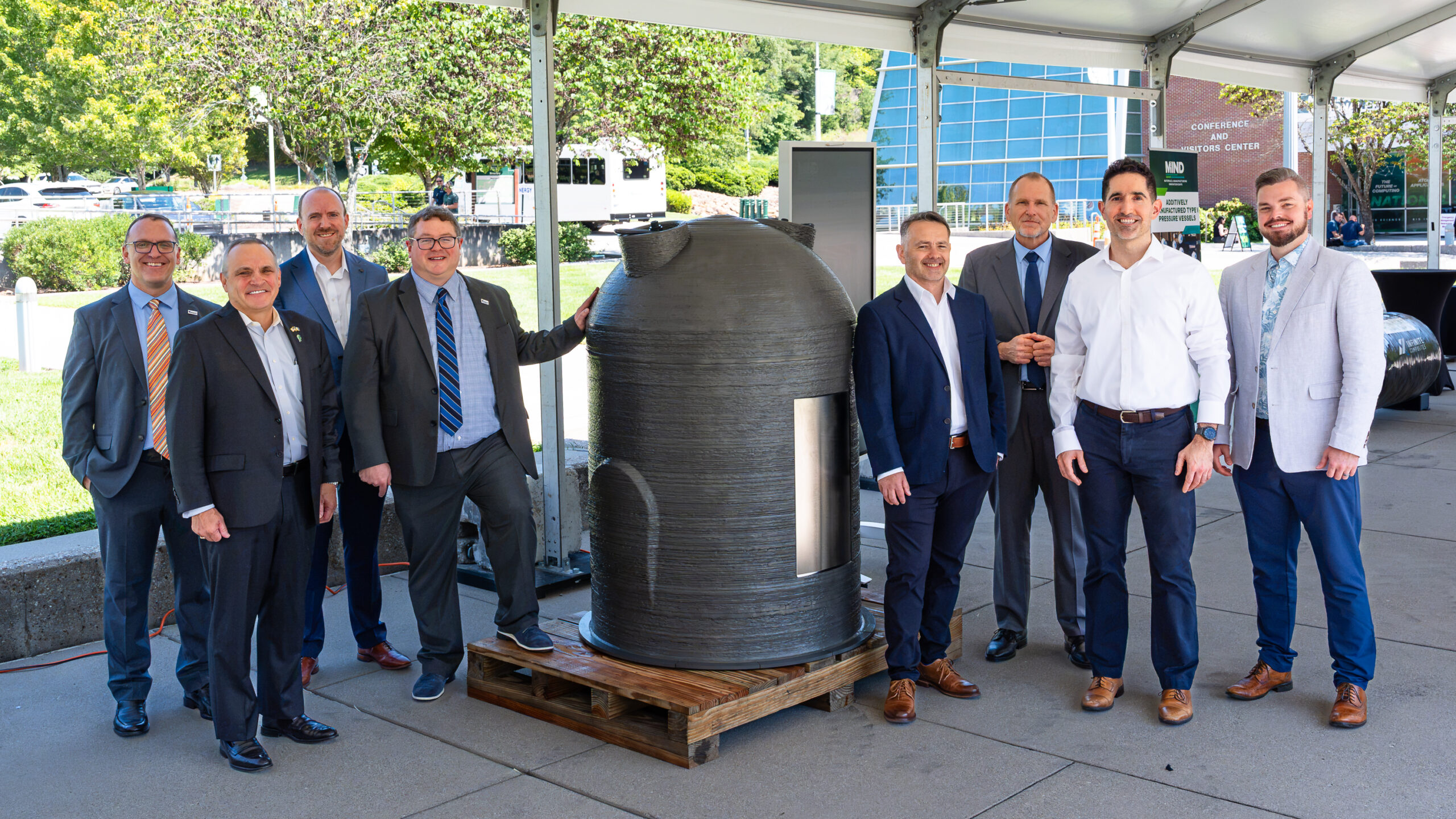 ORNL and INL leaders stand beside a 3D-printed pressure vessel.
