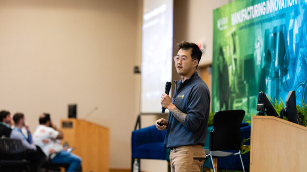 An Innovation Crossroads entrepreneur presents a company pitch onstage to attendees in the Tennessee Rooms.