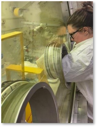 Researcher works with equipment inside a laboratory glovebox.